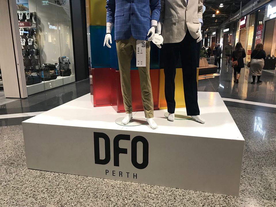 Mannequins on a white branded display plinth in a shopping centre