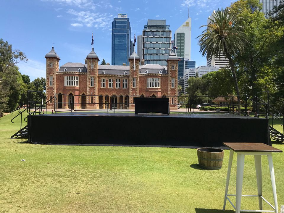 Event stage on a city lawn in front of a heritage building