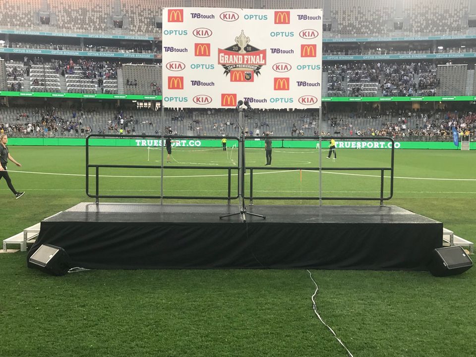Rolling presentation stage with handrails on a stadium field